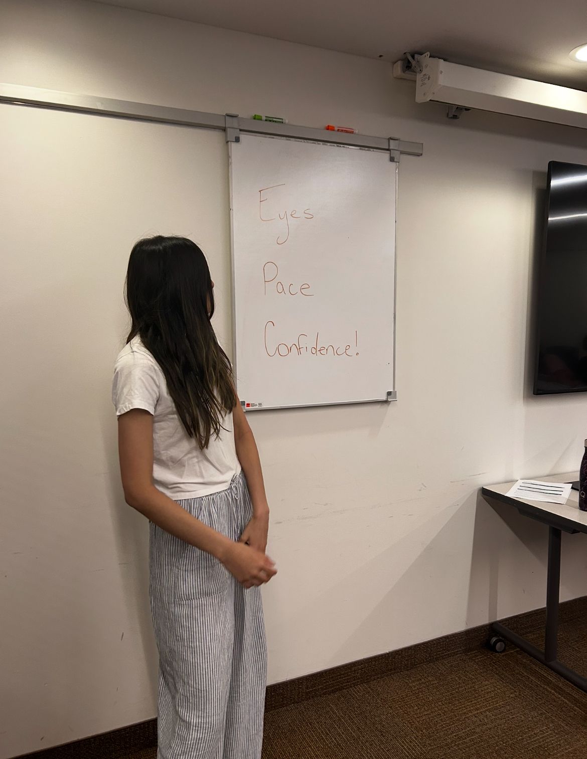 Student practicing in front of a whiteboard reading Eyes, Pace, Confidence